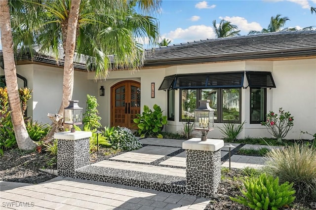 view of exterior entry featuring french doors and stucco siding