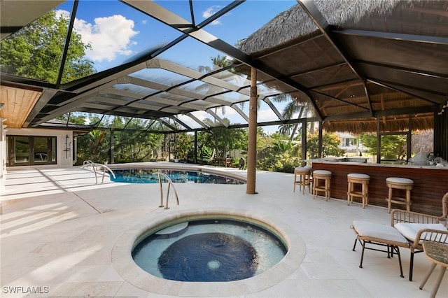 outdoor pool with a lanai, a patio area, and an in ground hot tub