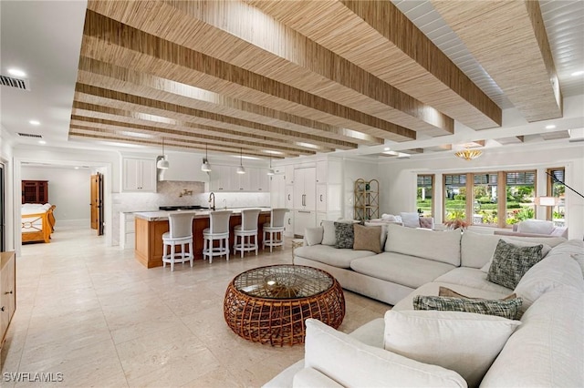 living area with beamed ceiling, visible vents, and recessed lighting
