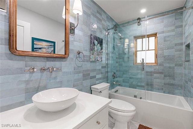full bathroom with toilet, combined bath / shower with glass door, vanity, and tile walls