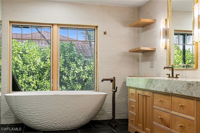 full bathroom with a freestanding bath, vanity, and tile patterned floors