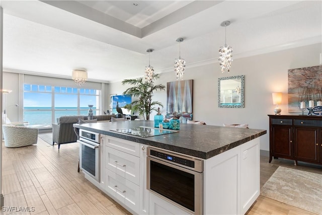 kitchen featuring dark countertops, light wood finished floors, white cabinetry, stainless steel oven, and black electric stovetop