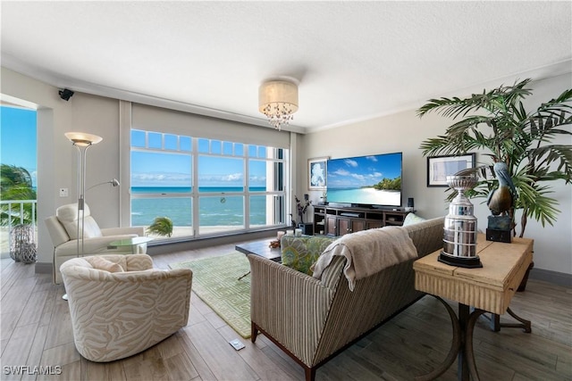 living area with a healthy amount of sunlight, wood finished floors, and an inviting chandelier