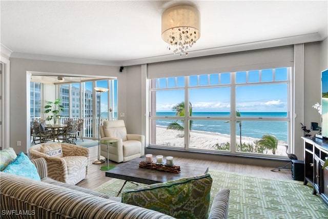 living room featuring a chandelier, a water view, wood finished floors, and ornamental molding