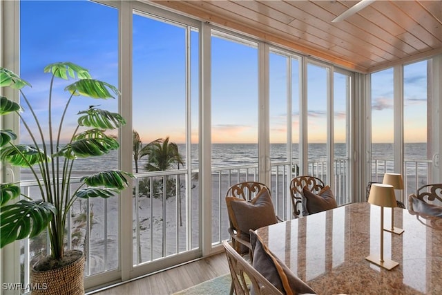 sunroom featuring wood ceiling and a water view