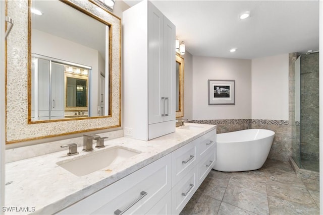 full bath with double vanity, recessed lighting, a stall shower, a freestanding tub, and a sink