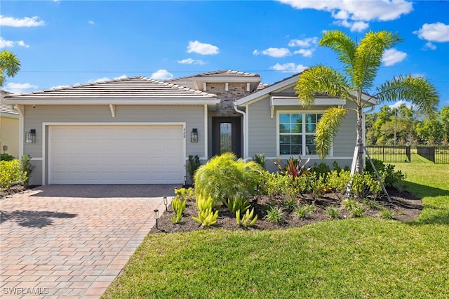 view of front of property featuring fence, a front lawn, a garage, a tile roof, and decorative driveway