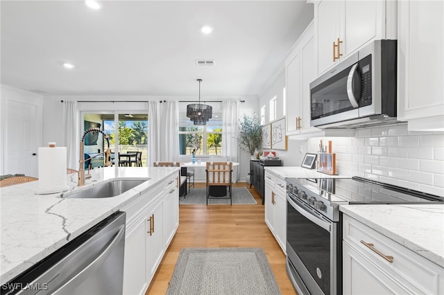 kitchen featuring a sink, stainless steel appliances, light wood-style flooring, and white cabinetry