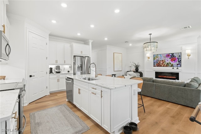 kitchen featuring open floor plan, light wood-style flooring, appliances with stainless steel finishes, and a sink