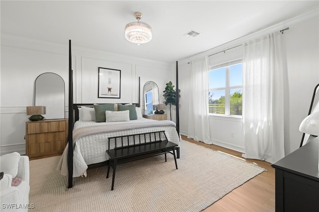 bedroom featuring light wood-type flooring, visible vents, and crown molding