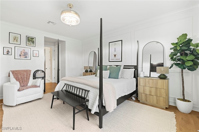 bedroom featuring visible vents, light wood-style floors, and crown molding