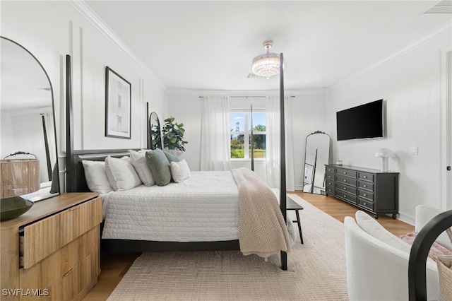 bedroom with visible vents, wood finished floors, baseboards, and ornamental molding