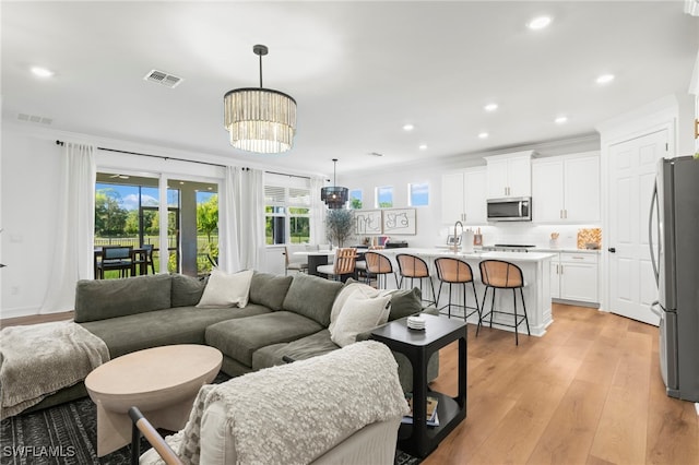 living room with recessed lighting, visible vents, crown molding, and light wood finished floors