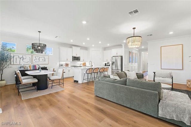 living area with visible vents, a chandelier, ornamental molding, recessed lighting, and light wood-style floors