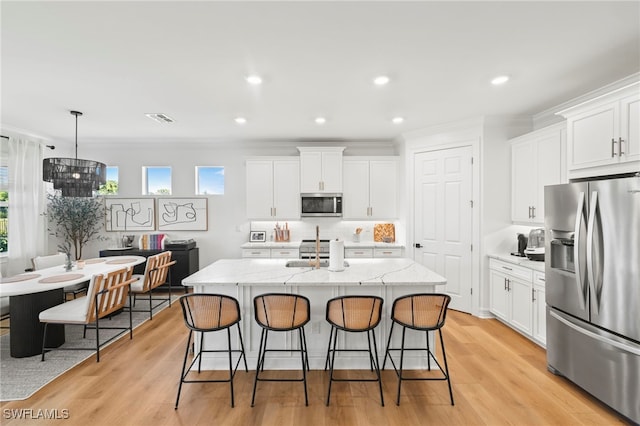 kitchen featuring visible vents, white cabinetry, appliances with stainless steel finishes, and a breakfast bar area