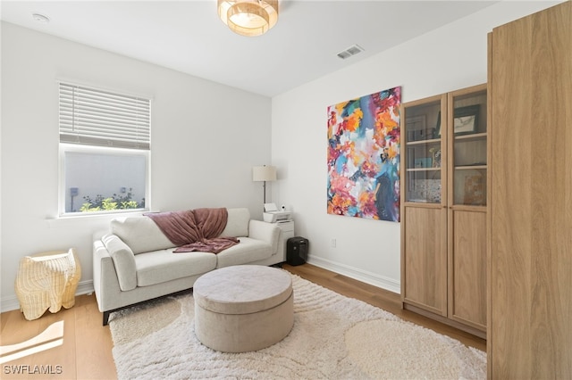 living area with visible vents, baseboards, and wood finished floors