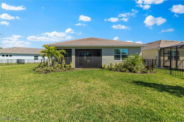 rear view of property featuring a yard, a sunroom, a fenced backyard, and stucco siding