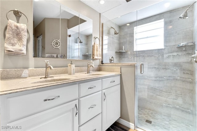 full bathroom with double vanity, a stall shower, and a sink