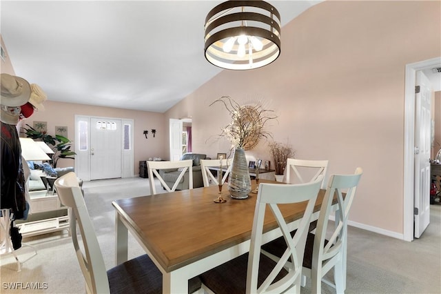 dining area with lofted ceiling, light colored carpet, and baseboards