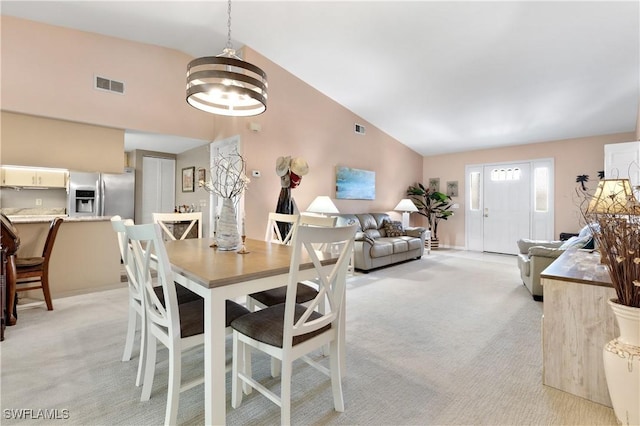 dining space featuring high vaulted ceiling, visible vents, a chandelier, and light colored carpet