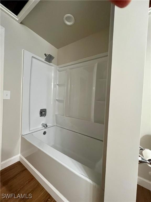 bathroom with  shower combination, wood finished floors, and baseboards