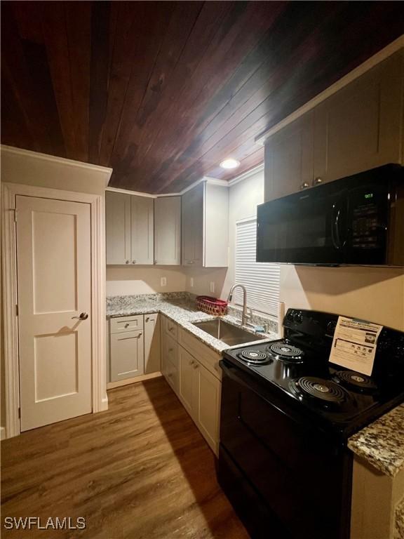 kitchen with wood ceiling, light stone counters, dark wood-style flooring, black appliances, and a sink