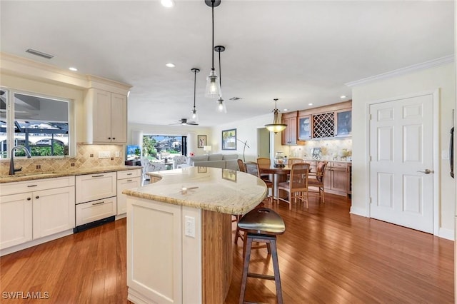 kitchen with a kitchen bar, visible vents, a sink, and ornamental molding