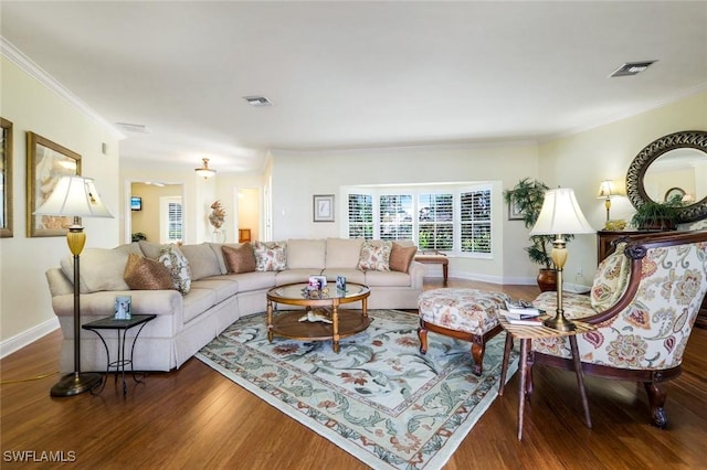 living room with baseboards, crown molding, visible vents, and wood finished floors