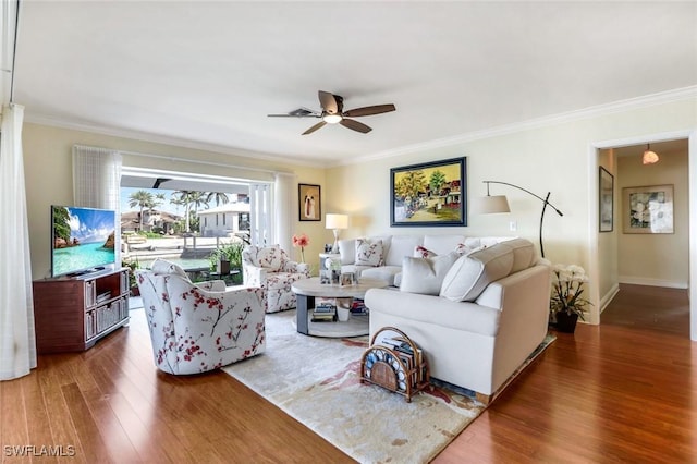 living room featuring ceiling fan, baseboards, wood finished floors, and crown molding