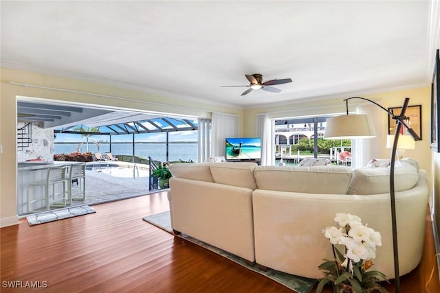 living area featuring a ceiling fan, wood finished floors, a sunroom, and crown molding