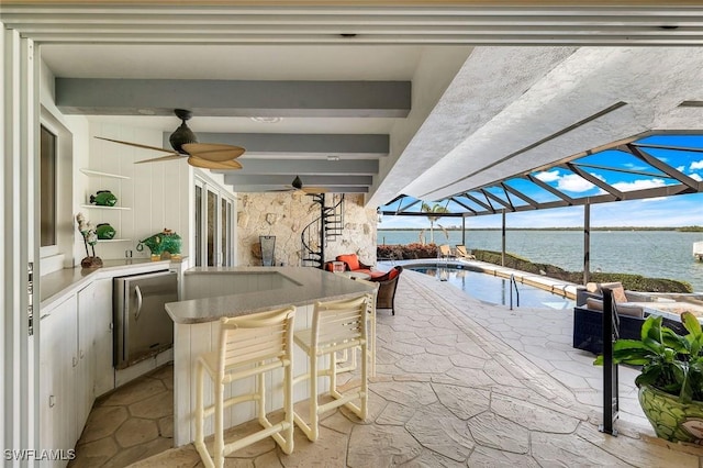 view of patio featuring a water view, outdoor dining space, glass enclosure, ceiling fan, and an outdoor pool