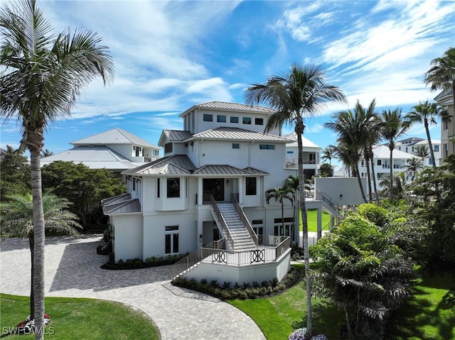 view of front of house with stairway, metal roof, a standing seam roof, decorative driveway, and stucco siding