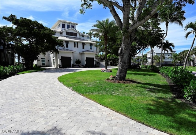 view of front facade with a standing seam roof, metal roof, a front lawn, and decorative driveway