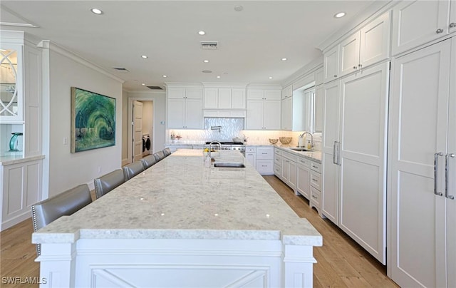 kitchen featuring ornamental molding, light wood finished floors, a sink, and white cabinetry
