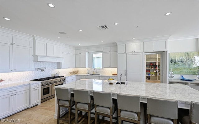 kitchen featuring white cabinetry, backsplash, visible vents, and double oven range
