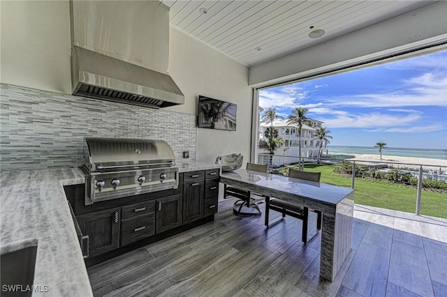 view of patio / terrace with outdoor dining area, an outdoor kitchen, a view of the beach, area for grilling, and a water view