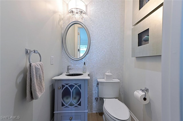 bathroom with toilet, a notable chandelier, and vanity