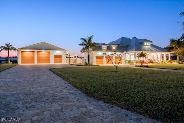 view of front of property with decorative driveway, a yard, fence, metal roof, and a garage