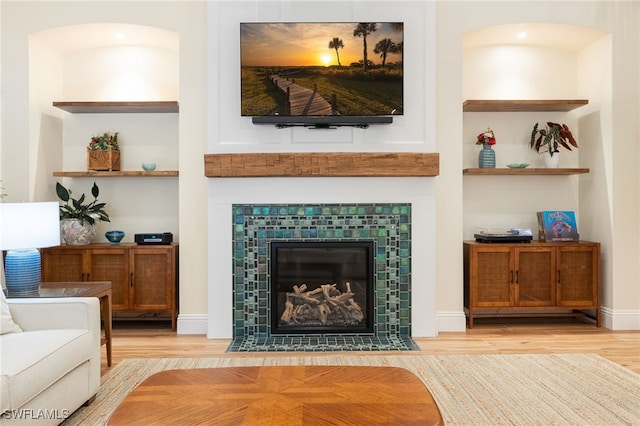 living area with a fireplace, baseboards, and wood finished floors