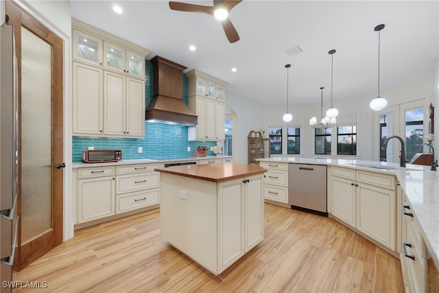 kitchen featuring light wood-style flooring, butcher block countertops, a sink, stainless steel dishwasher, and custom exhaust hood