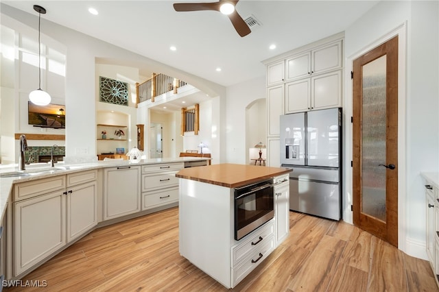 kitchen with arched walkways, a sink, light wood-style flooring, and stainless steel fridge with ice dispenser