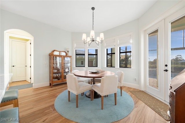 dining room featuring a notable chandelier, baseboards, and light wood-style floors