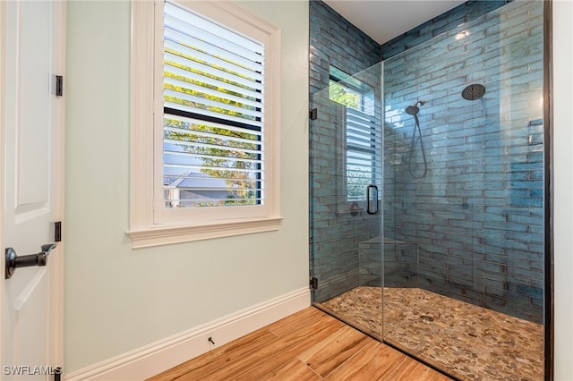 bathroom featuring a stall shower, baseboards, and wood finished floors