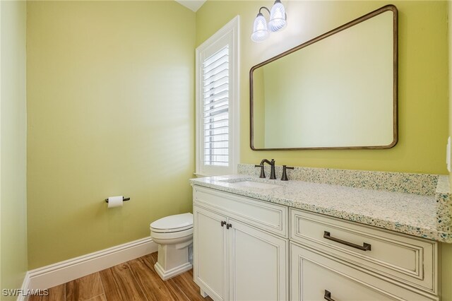 bathroom with baseboards, vanity, toilet, and wood finished floors