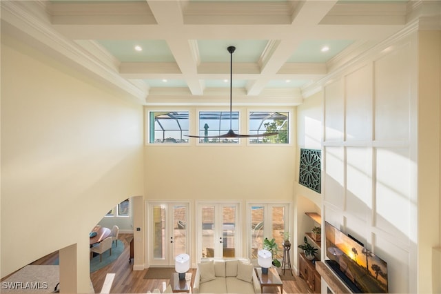 living area with a towering ceiling, coffered ceiling, beamed ceiling, and french doors