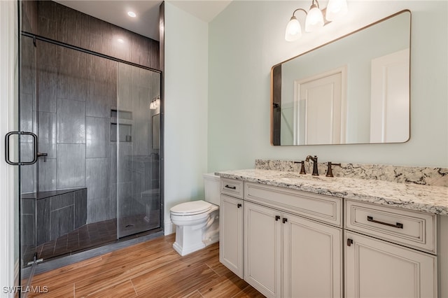 bathroom featuring vanity, a shower stall, toilet, and wood finished floors