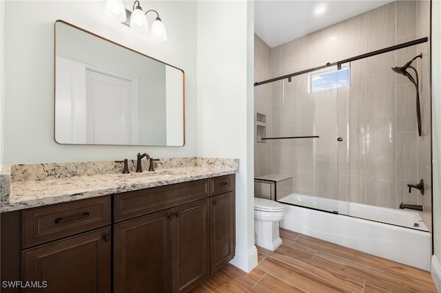 full bathroom with vanity, bath / shower combo with glass door, wood finished floors, and toilet