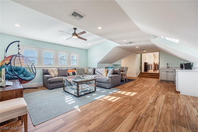 living room with light wood-type flooring, visible vents, vaulted ceiling, and recessed lighting