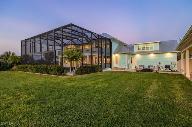 back of property at dusk with a lanai and a yard