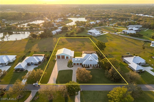 aerial view at dusk featuring a residential view and a water view